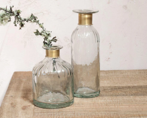Zwei Vasen aus Glas auf einem Holztisch. Sie haben einen goldenen Messingring an der Öffnung